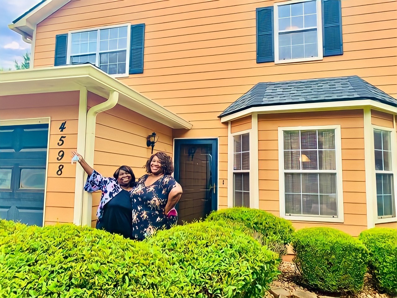 Anita James (left) and her daughter (right) smile brightly in front of their new home.