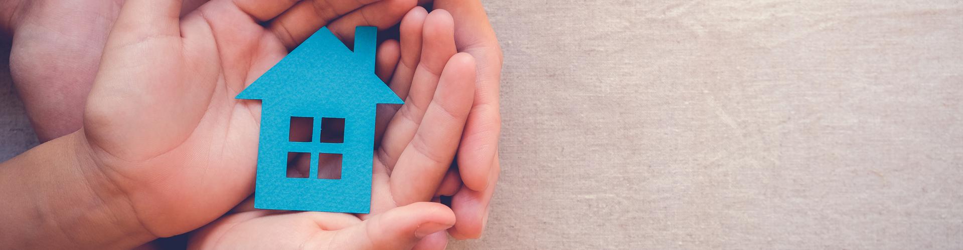 Child and adult holding blue paper image of a home